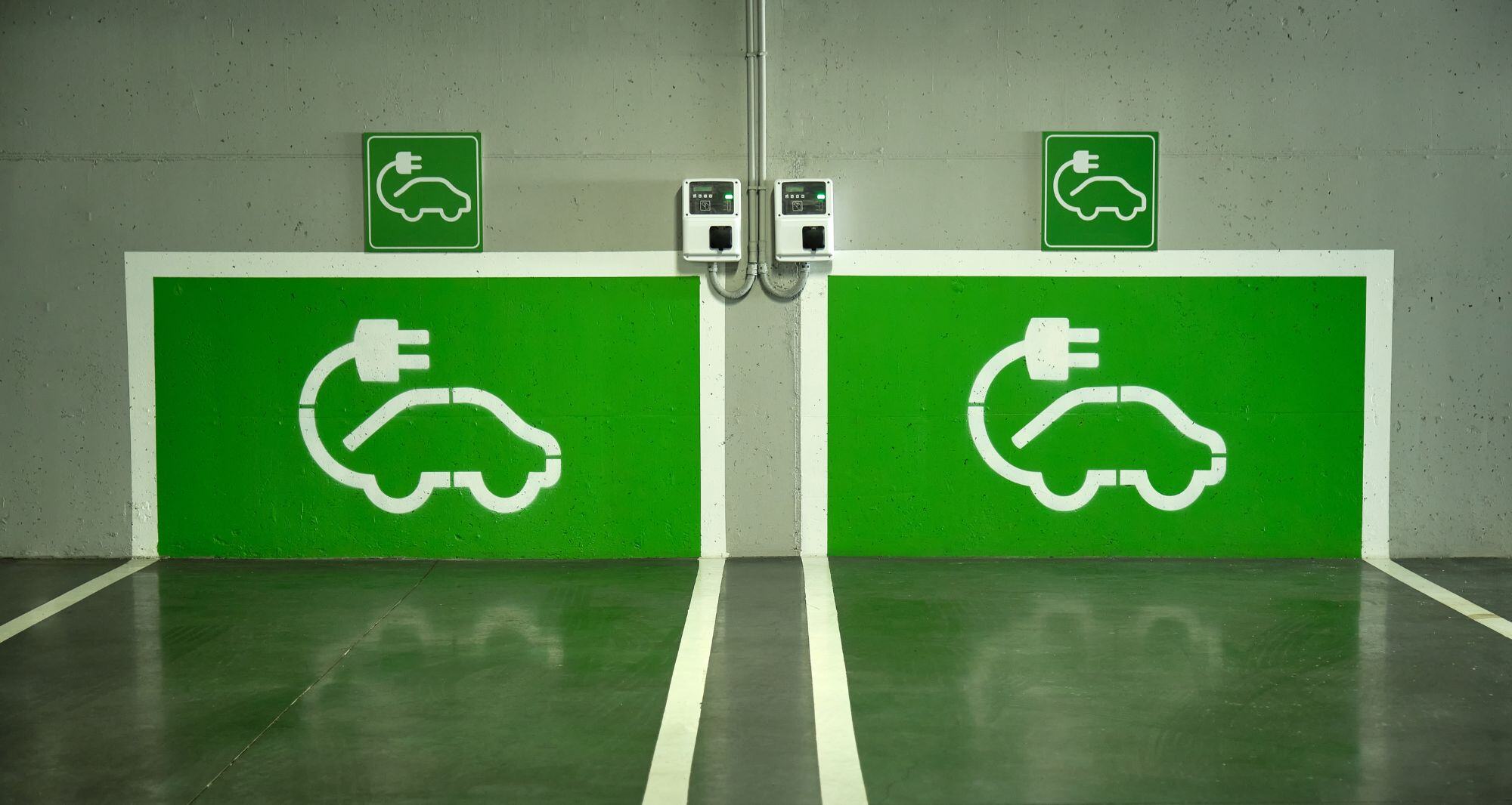 image d'un parking avec deux bornes électriques peintes en vert sur le mur